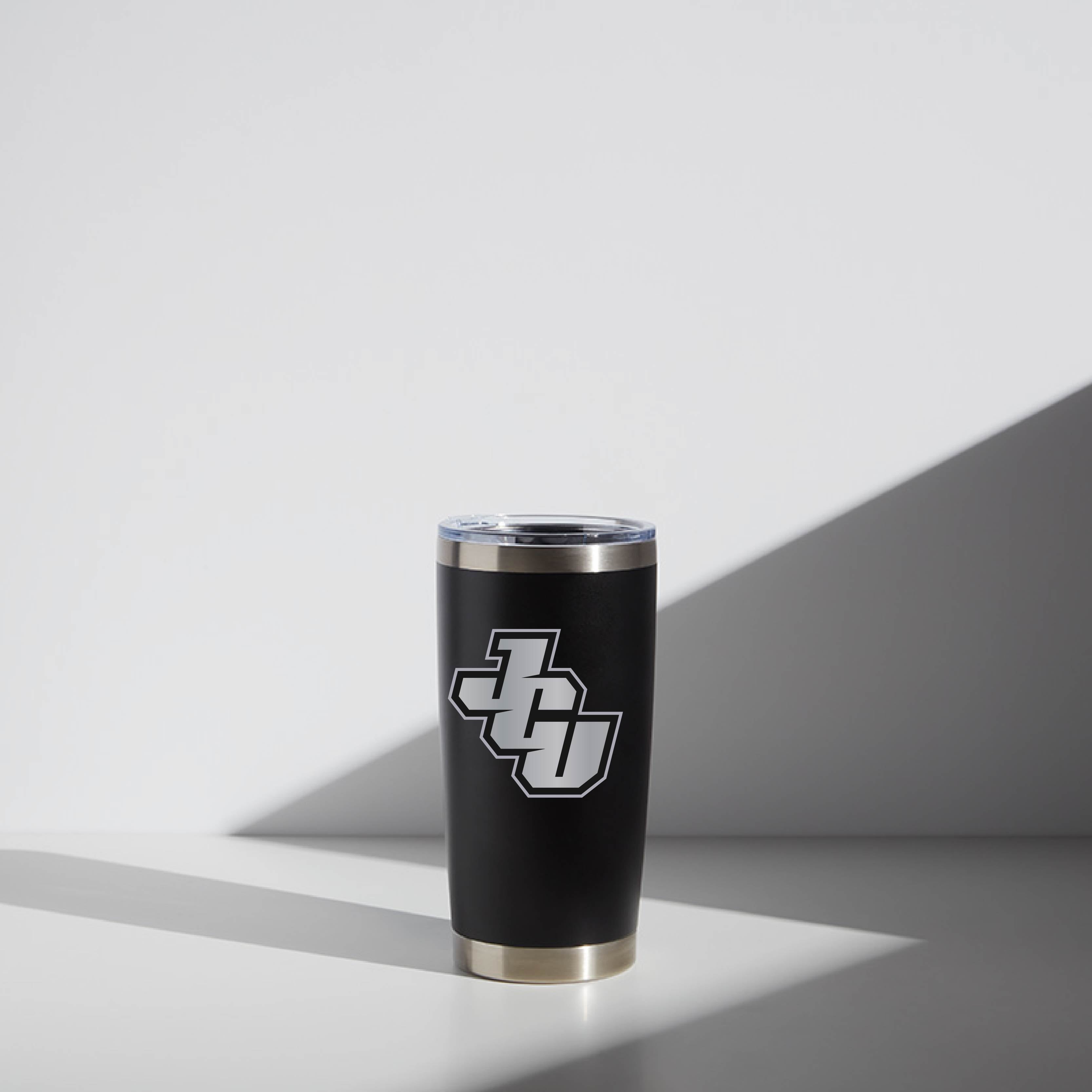 20 oz WATR tumbler in black with a silver John Carroll University JCU logo, featuring a clear lid, displayed under a soft light with geometric shadows.