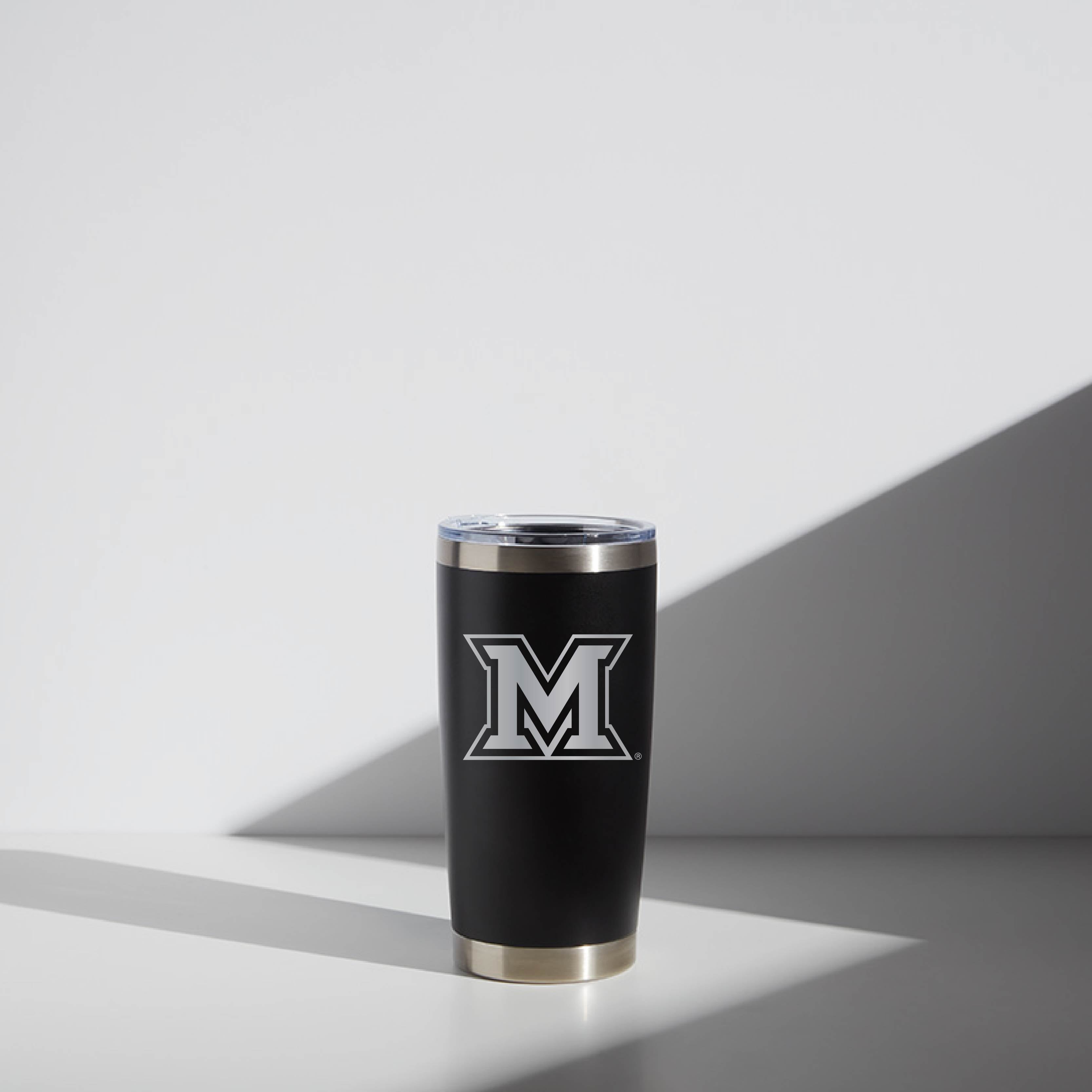 Alt text: "20 oz WATR Tumbler Block Miami featuring a sleek black and silver design with a prominent 'M' logo, displayed against a minimalistic white background with subtle shadow play."