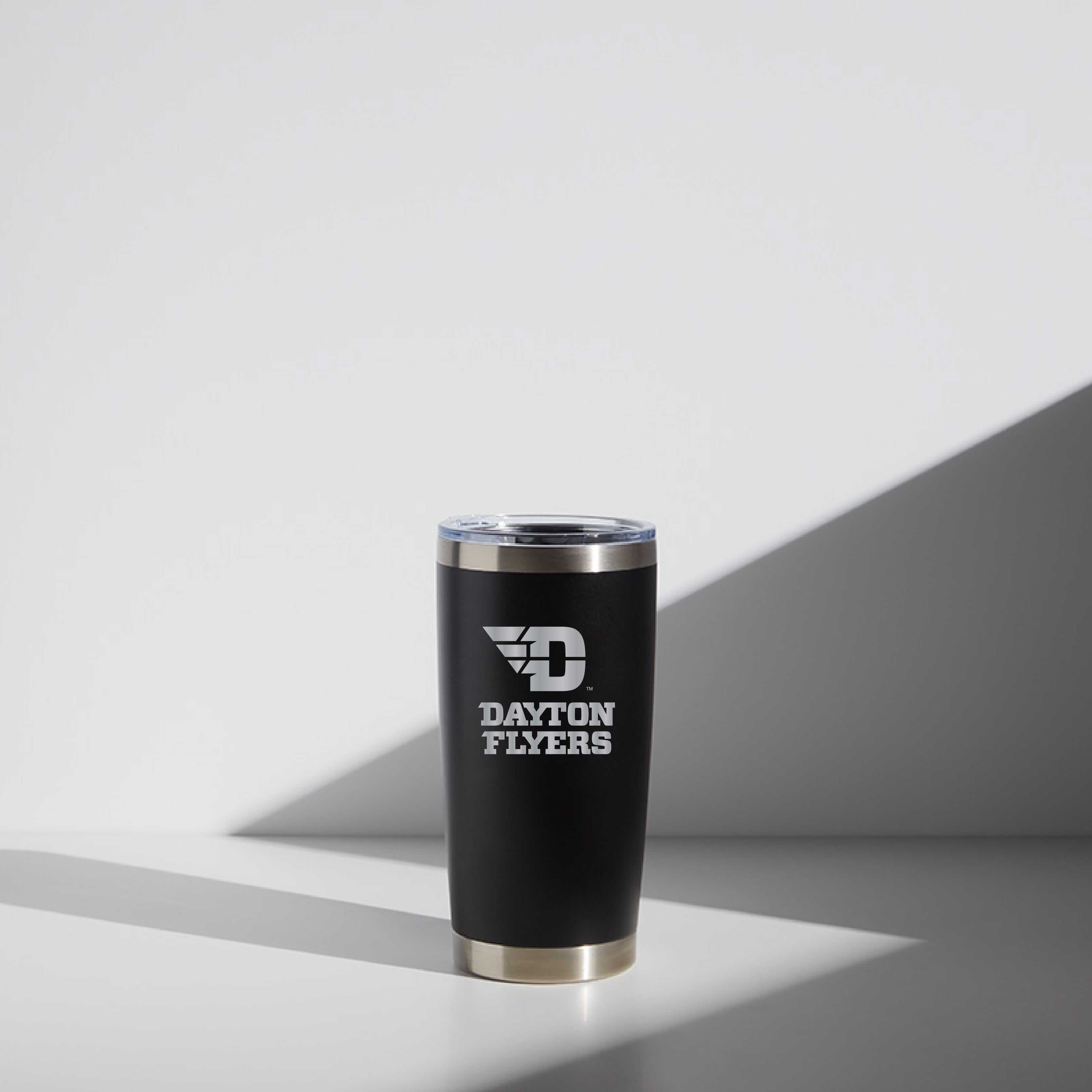 20 oz WATR Tumbler with Dayton Flyers logo in black and stainless steel design, featuring a clear lid, displayed on a white surface with a shadow cast to the right.