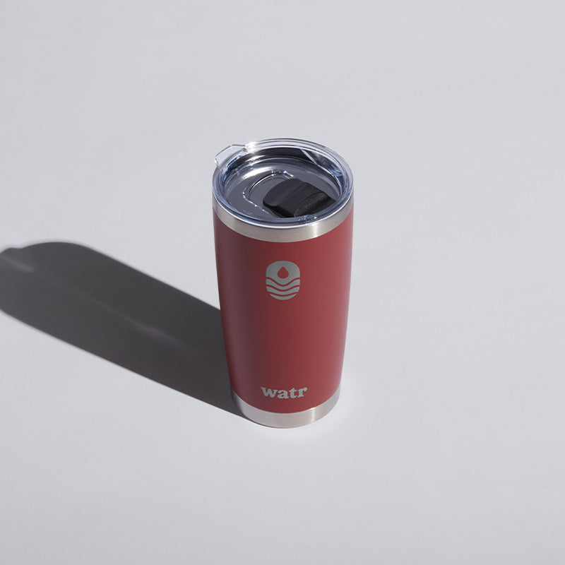 Alt text: "Red 20 oz WATR branded tumbler with a clear sliding lid, prominently featuring the company's logo on a light gray background."
