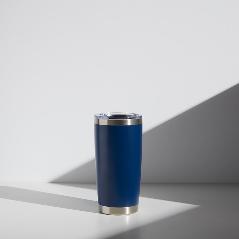 Alt text: "20 oz personalized stainless steel tumbler in navy blue with a clear lid, ideal for teacher gifts, shown in a well-lit setting with shadow play on a white surface."