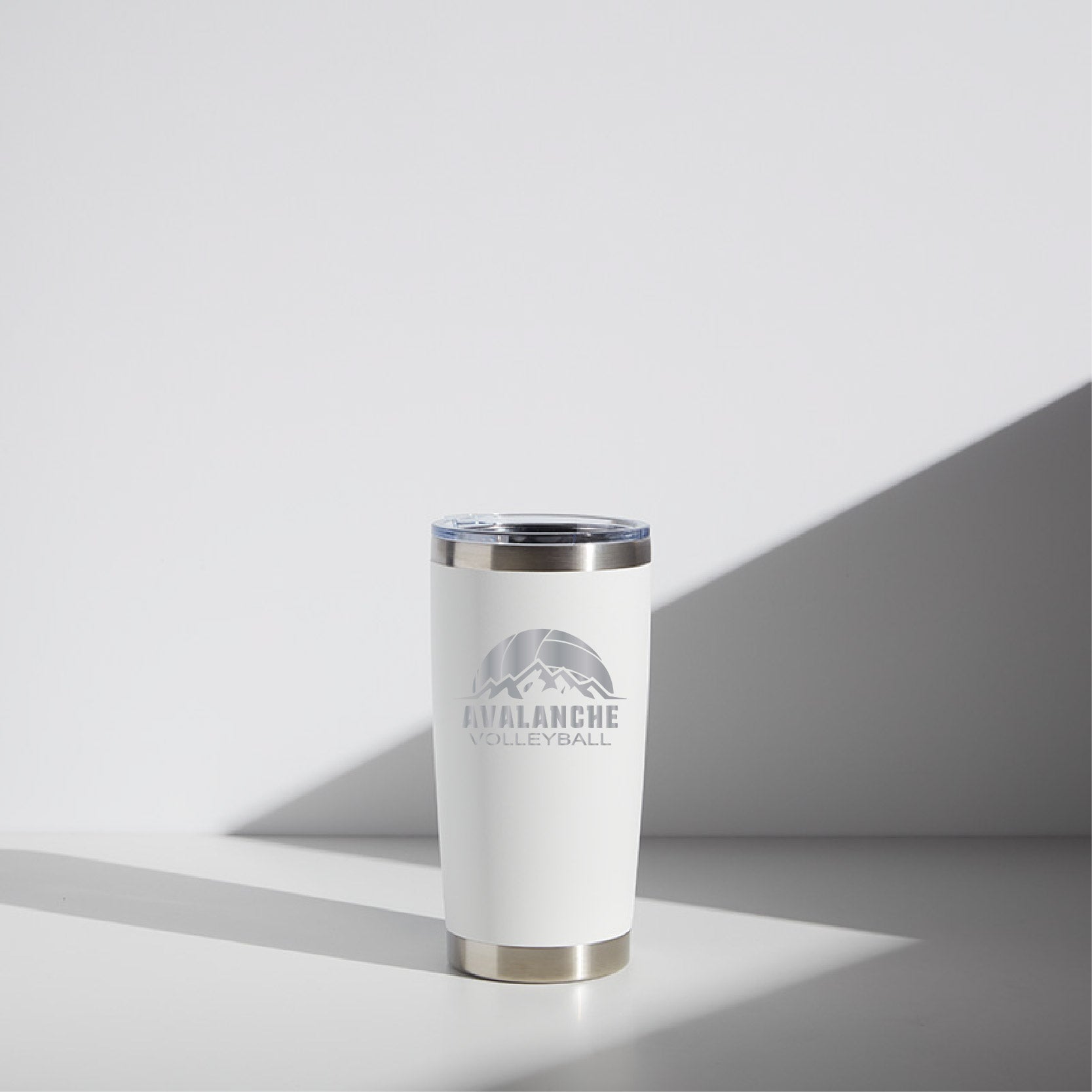 20 oz stainless steel tumbler for Avalanche Volleyball with logo, featuring a silver rim and clear lid, in a minimalistic white background.