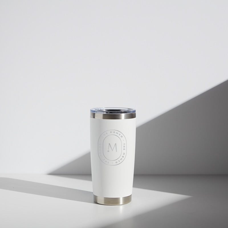 Alt text: "20 oz white and silver WATR stainless steel tumbler branded with MomCo logo, sitting in a well-lit room casting a soft shadow."