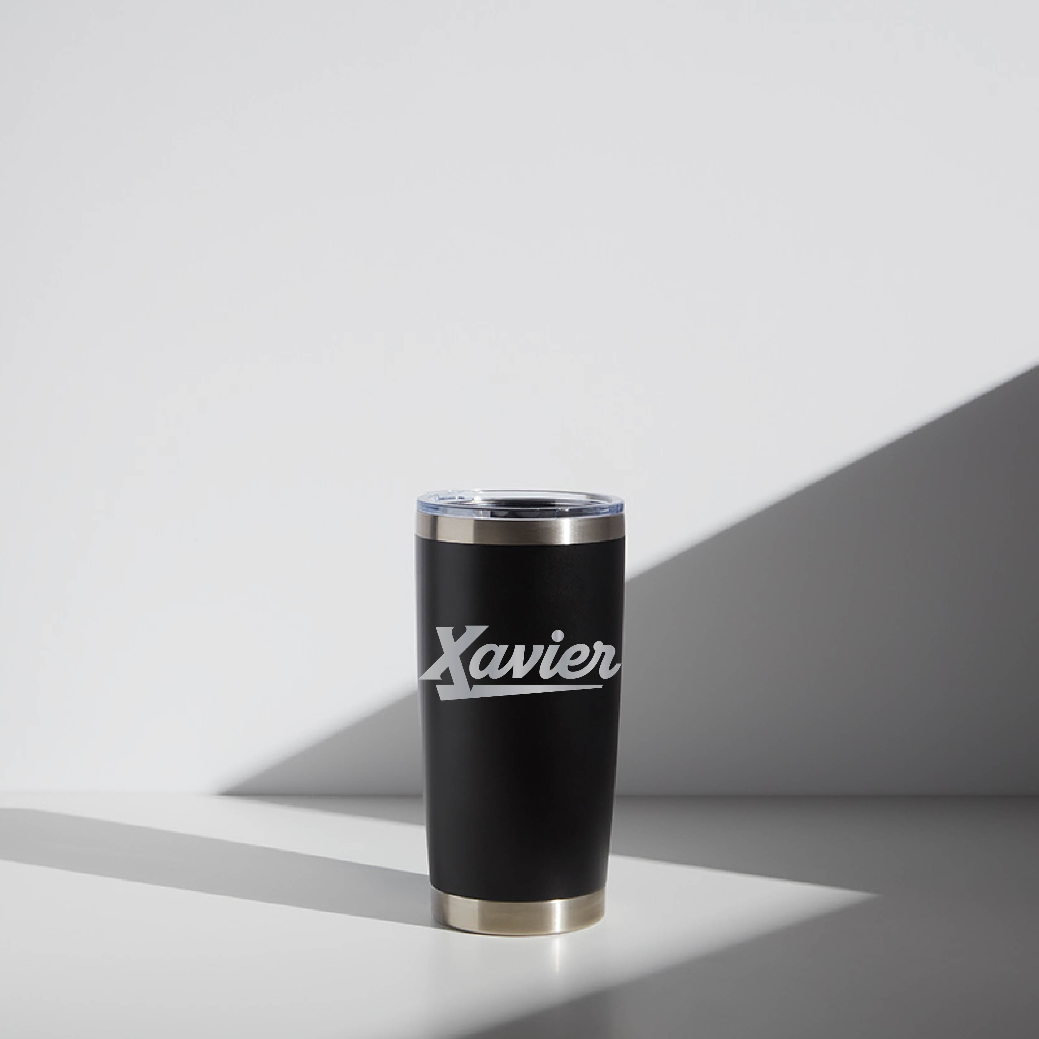 Alt text: "20 oz WATR Tumbler Script Xavier featuring an elegant matte black finish with 'Xavier' scripted in white on the side, a clear lid, and gold trim at the base, positioned against a minimalist white background with