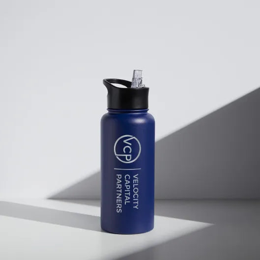 Blue water bottle custom etched with Velocity Capital Partners logo on a gray background